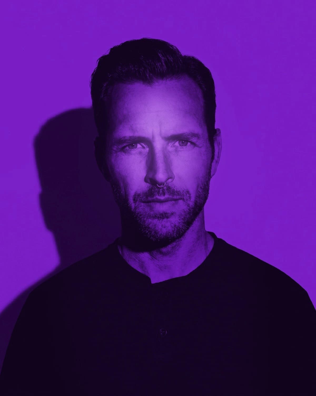 The Frequency Architect — Artist 001 — beneath a single violet light bar, wired earphones in, composed and direct.